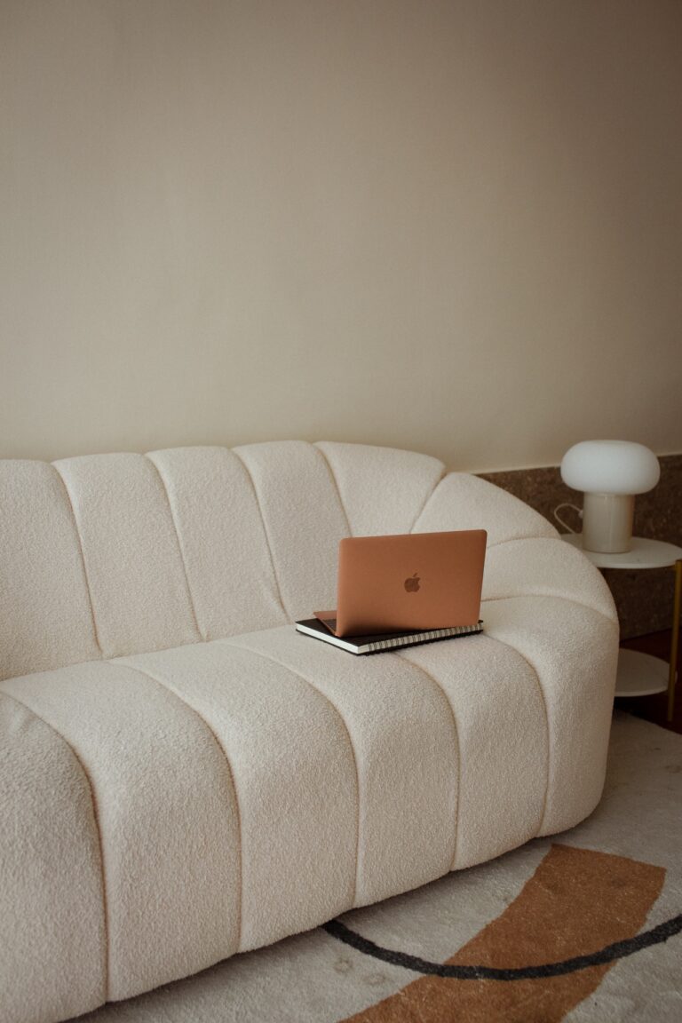 laptop-sits-on-stack-of-books-on-boucle-white-sofa