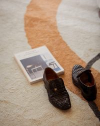 pair-of-brogue-shoes-sit-on-rug-next-to-magazine